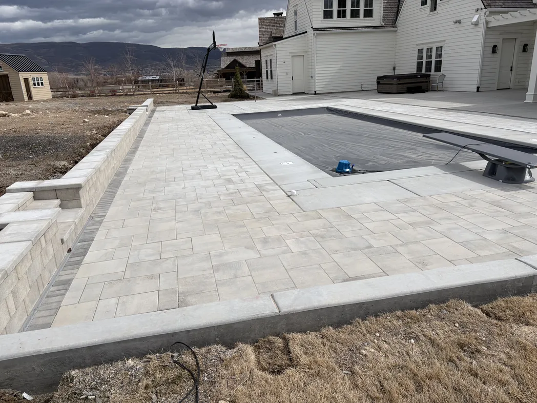 Large finished paver patio around a residential pool with mountain backdrop